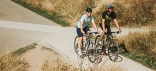 A woman and a man are cycling along a path.