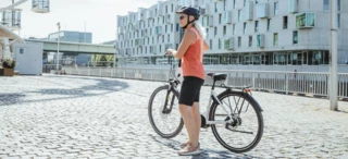 A woman stands with her bike in a square