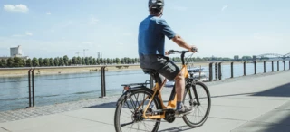 Radfahrer fährt an einem Ufer entlang