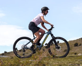 A woman rides her bike up a hill